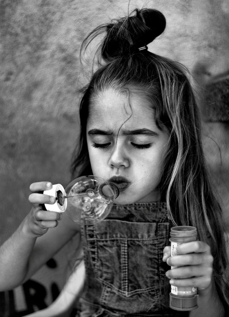 Niña soplando burbujas.